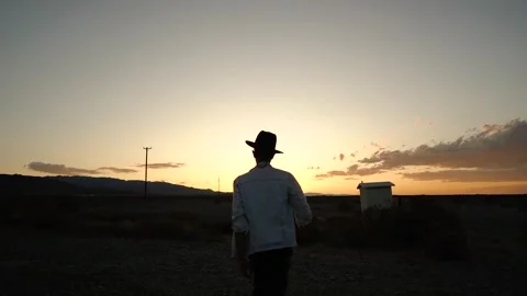 Man in Hat Walking Toward Sunset Silhouette Video stock 327447434