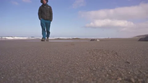 Man in a hat walks on the sand beach in cold sunny morning nature Stock Footage 235918102