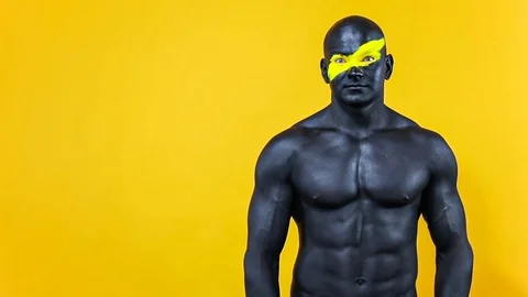 Man have a good idea. Bodybuilder athlete with yellow face art and black body Stock Footage 128883271
