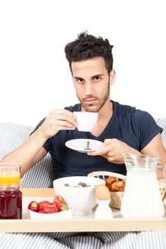 Man is having breakfast in the bed Stock Photos