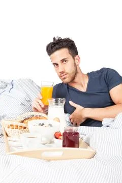 Man is having breakfast in the bed Stock Photos