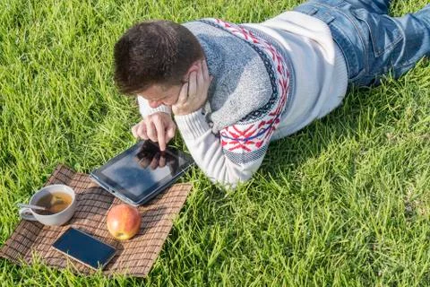 Man having breakfast lying on the grass in the garden with technology Stock Photos