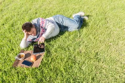 Man having breakfast lying on the grass in the garden with technology Stock Photos