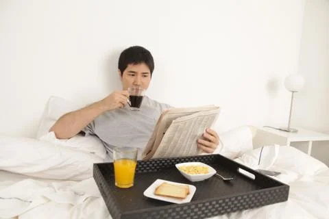 Man having a breakfast while reading the newspaper 写真素材