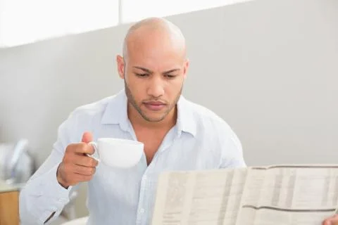 Man having coffee while reading newspaper at home Stock Photos