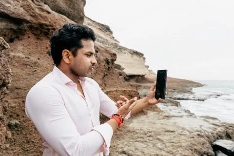A man is having a conversation through a video call at the beach while on v.. Stock Photos
