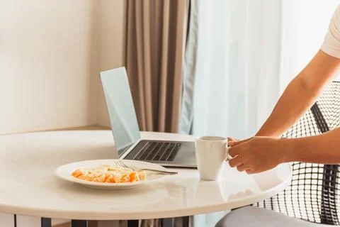 Man having cup of coffee with fresh fruits while working on laptop. Stock Photos