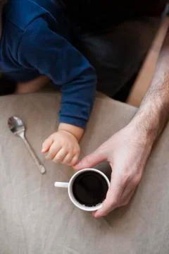 Man having cup of coffee while holding toddler son, cropped 스톡 사진