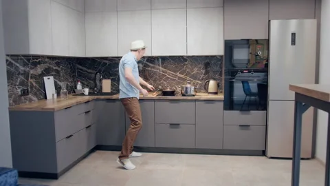 Man having fun in the kitchen while cooking, dancing and singing with a ladle in Stock Footage 166984100