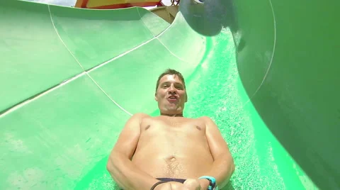 Man having fun sliding down a waterslide in public swimming pool Stock Footage 64146195