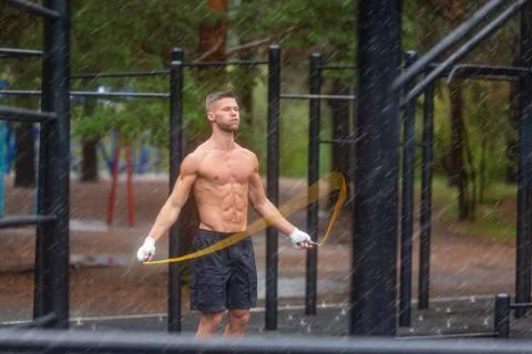 Man having hard workout with a jumping rope outdoor in a rainy day. Foto stock