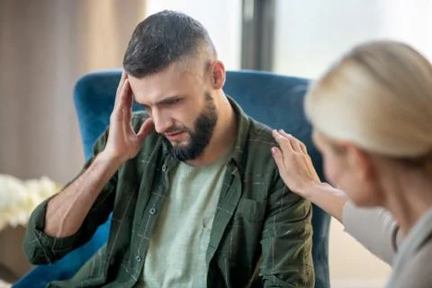 Man having headache while sharing concerns with psychoanalyst Stock Photos