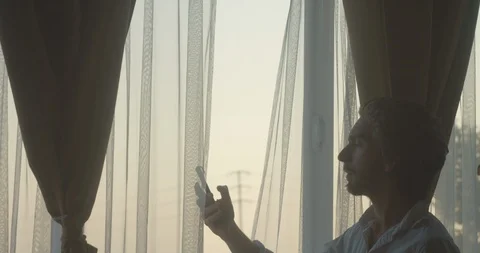 Man having an intense conversation on phone next to window at dusk 2 库存影片 128522333