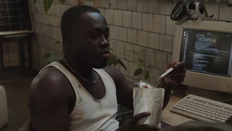 Man Having Meal and Coding on Computer in Post Apocalypse Shelter Stock Footage 266396150