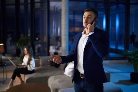 Man having mobile talk while woman working on laptop Stock Photos