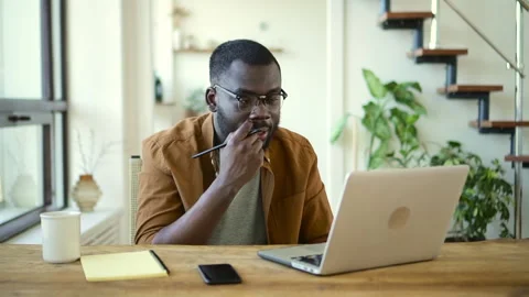 Man having online talk in front of laptop and sitting at table in apartment Stock Footage 156749632