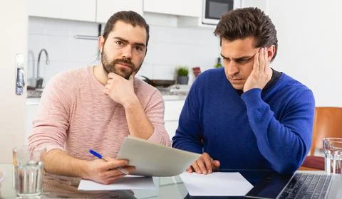 Man having problems with some documents, worriedly discussing with friend at Stock Photos