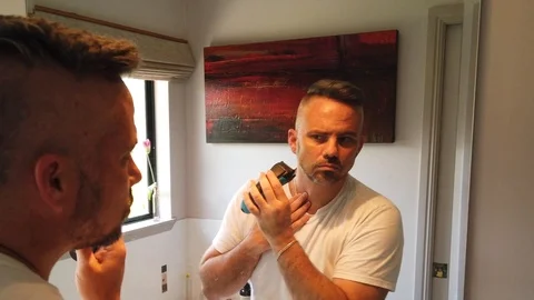 Man having a shave in the mirror in slow motion, feeling how smooth it is Stock Footage 121871405
