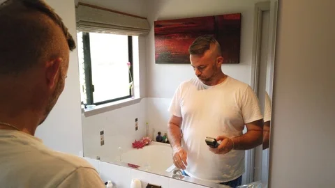 Man having a shave in the morning in the mirror, using an electric razor, Stock Footage 121875183