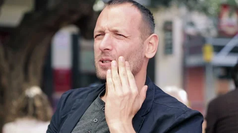 Man having toothache while drinking hot coffee in city HD Stock Footage 32890580