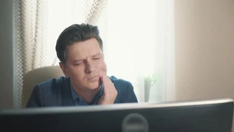 Man having toothache while sitting at computer Stock Footage 171963299