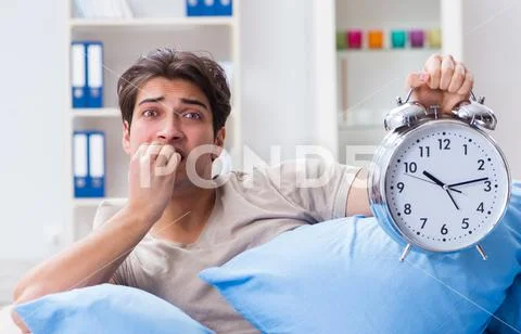 Man having trouble waking up with alarm clock Stock Photos