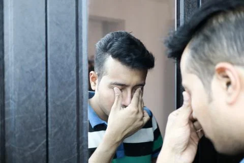 A man with head down in front of a mirror in depressed mood with selective fo Stock Photos