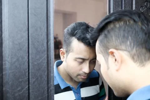 A man with head down in front of a mirror in depressed mood with selective fo Stock Photos
