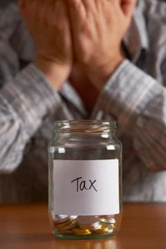 Man With Head In Hands Looking At Jar Labelled Tax Stock Photos