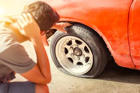 A man headache when car breakdown and wheel flat tire in parking Stock Photos