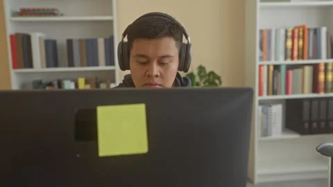 Man with headphones at computer looking at screen, face focused on monitor .. Stock Footage 347799956