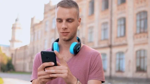 Man with headphones texting message outdoors Stock Footage 99865099