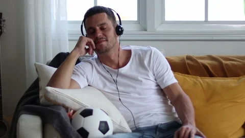 A man in Headphones Using Smartphone Sitting On sofa Indoor. Stock Footage 163088020
