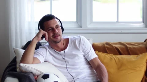 A man in Headphones Using Smartphone Sitting On sofa Indoor. Stock Footage 163088037