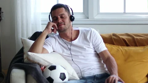 A man in Headphones Using Smartphone Sitting On sofa Indoor. Stock Footage 163088056
