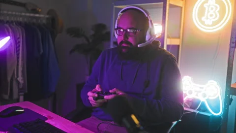 Man with headset holding controller, fingers pressing buttons while seated .. Stock Footage 347690289