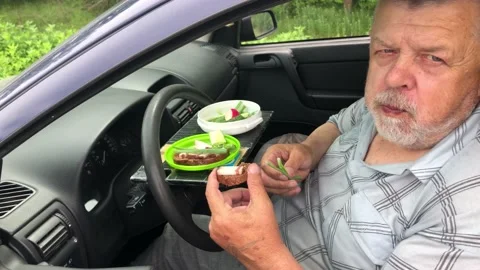 Man healthy eating while sitting inside of passenger car on driver seat Video stock 157556228