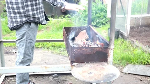 Man heat his hands above barbecue BBQ grill with flaming fire and ember charcoal Stock Footage 130968341