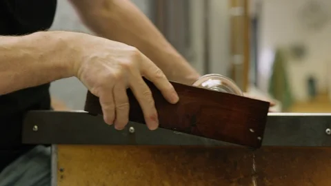 Man heating and shaping a hot glass on blow pipe Stock Footage 107891860
