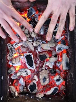 The man heats his hands in front of an open fire. Camping concept with outdoo Stock Photos