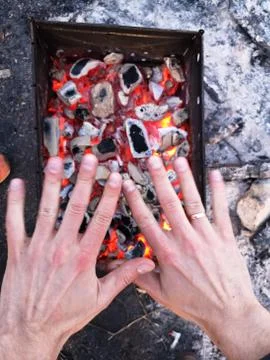 The man heats his hands in front of an open fire. Camping concept with outdoo Foto stock