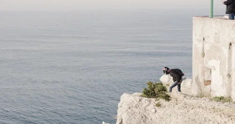 Man in helmet checking wind direction before jumping off cliffs with parachute 스톡 동영상 160503585