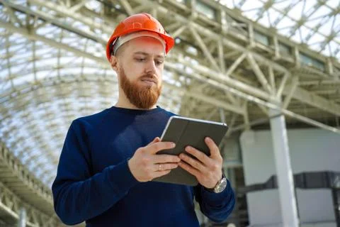 A man in a helmet in a large space with a tablet Stock Photos