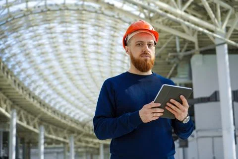 A man in a helmet in a large space with a tablet Stock Photos