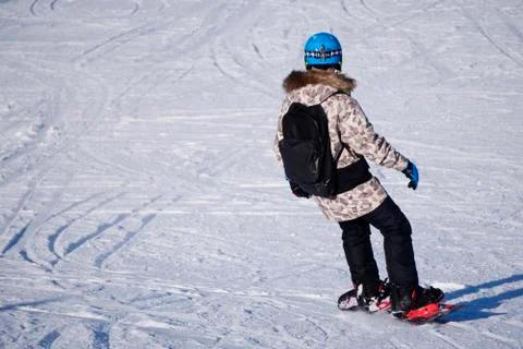 A man with a helmet in warm bright clothes goes snowboarding against the back Stock Photos