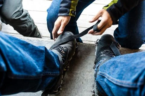 Man helping another man put on snow hiking acessories, partial v Stock Photos