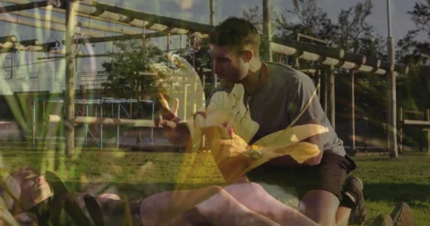 Man helping another person on ground overlaid with yellow flower animation Stock Footage 305486930