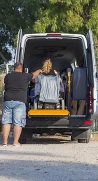 The man is helping the disabled person to step down from the car. Stock Photos