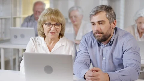Man Helping Elderly Woman in Computer Class Stock Footage 107978519
