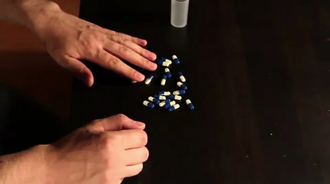 Man hesitantly pours a bottle of pills on the table Видео 36640438